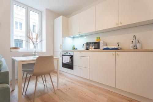 une cuisine avec des placards blancs et une table avec une chaise dans l'établissement Very nice apartment for 2 people, Le Macon Park free, à Mulhouse