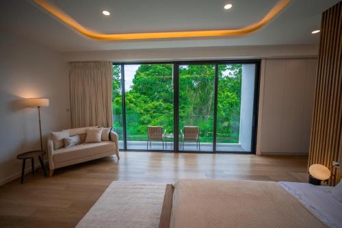 een woonkamer met een bank en een groot raam bij Brand new 3 bedrooms villa in Ko Samui