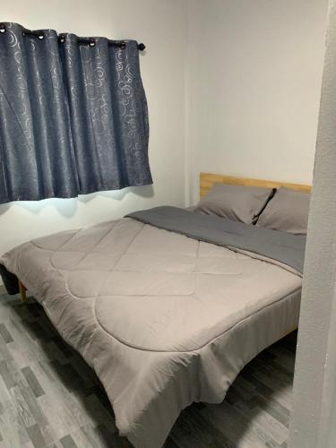 a bed in a bedroom with a black curtain at KHUN CHUAT'S HOUSE in Ban Nong Ben