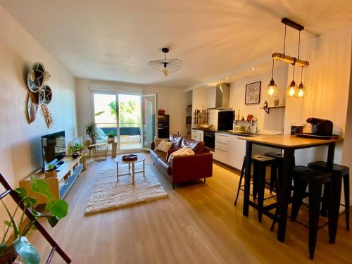 - une cuisine et un salon avec une table et un comptoir dans l'établissement Joli appartement cosy , terrasse, PK privé, à Lunel