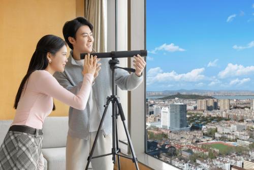 a man and woman looking into a window with a telescope at Shangri-La Nanjing in Nanjing