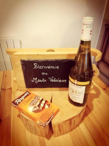 - une bouteille de vin et une boîte sur une table dans l'établissement Maison à la montagne Le Moulin Valaisan, à Novel