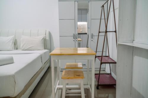 a bedroom with a bed and a stool next to a table at Minimalist Studio Room at Urbantown Serpong Apartment By Travelio in Tangerang