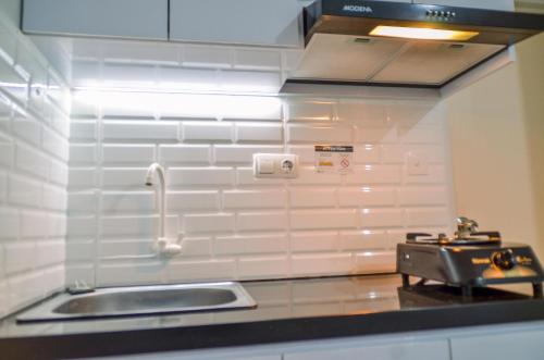a kitchen with a sink and a stove at Minimalist Studio Room at Urbantown Serpong Apartment By Travelio in Tangerang