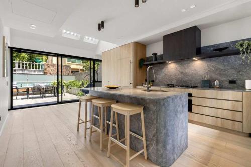 a kitchen with a large marble counter and stools at Beautiful Holiday Home w Private Terrace in Sydney