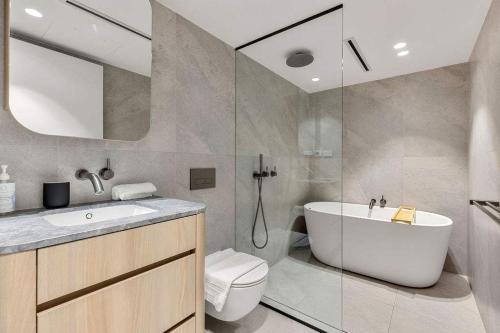 a bathroom with a tub and a toilet and a sink at Beautiful Holiday Home w Private Terrace in Sydney