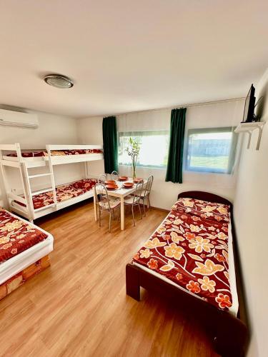 a room with two beds and a table and a dining room at Bamboo Rooms - Studios in Štúrovo