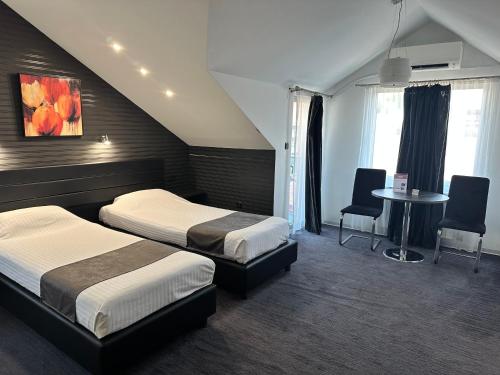 a hotel room with two beds and a table and chairs at Sienna Apartments in Skopje