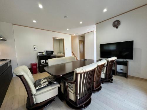 a living room with a table and chairs and a television at 白浜温泉付き貸別荘b-72 in Shirahama