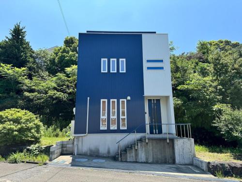 a blue building with a staircase in front of trees at 白浜温泉付き貸別荘b-72 in Shirahama