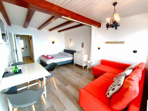 a living room with a red couch and a bedroom at MOOKI Mountain & Pool Gerlitzen Apartment in Kanzelhöhe