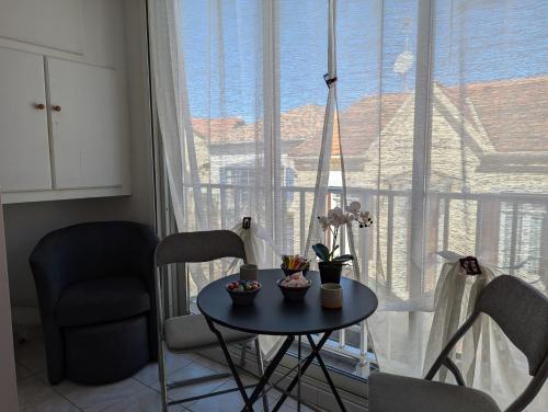 une table et des chaises dans une pièce avec une grande fenêtre dans l'établissement Sol-y-Days Vidourle rive droite, quartier calme 100m des plages et proche centre-ville, au Grau-du-Roi