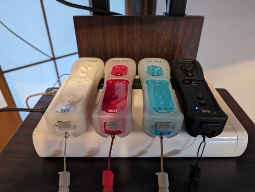four video game controllers are lined up on a table at 1棟貸切で家族仲間と焚火バーベキューを楽しめる古民家NanasawaBasshouse in Atsugi