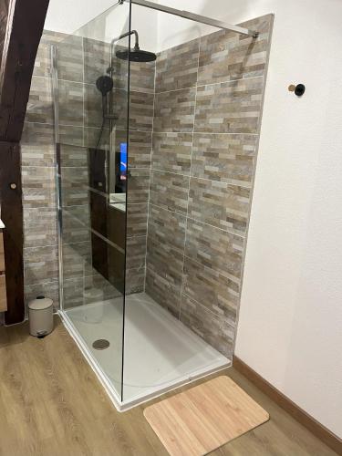 une douche avec une porte vitrée dans une pièce dans l'établissement La Pomme, à Douvres-la-Délivrande