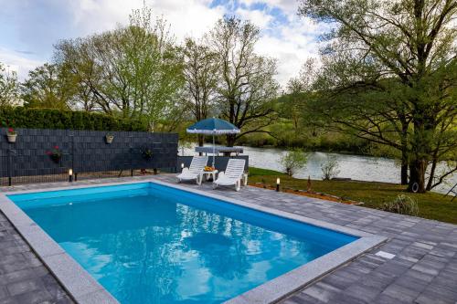 a swimming pool with two chairs and an umbrella at simply-una in Bihać