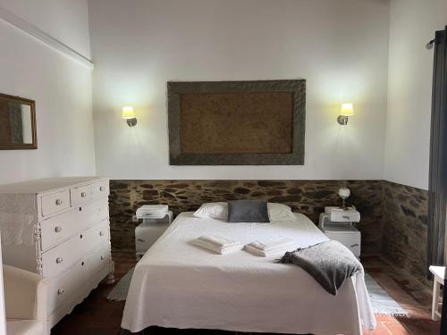 a bedroom with a white bed and a stone wall at Casa da Oliveira in Mértola