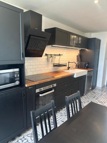 une cuisine avec des armoires noires, une table et des chaises dans l'établissement Cocon Azur avec vue panoramique sur mer - 3 chambres, à Nice