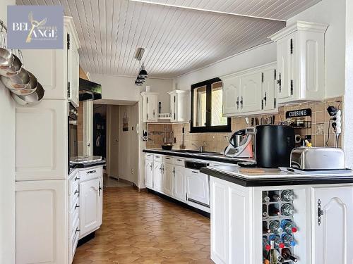 une cuisine avec des armoires blanches et un comptoir dans l'établissement Maison spacieuse et climatisée avec jacuzzi, à Molières-sur-Cèze