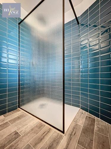 La salle de bains est pourvue d'une douche en verre et de carrelage bleu. dans l'établissement Maison spacieuse et climatisée avec jacuzzi, à Molières-sur-Cèze