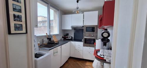 Elle comprend une petite cuisine avec des placards blancs et une fenêtre. dans l'établissement St André Centre Rouen Standing, à Rouen