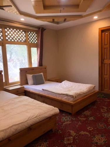 a bedroom with two beds and a window at HIKK Inn in Skardu
