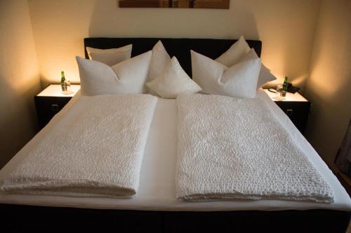 a bed with white pillows on top of it at Hotel Ammerland garni in Wilhelmshaven