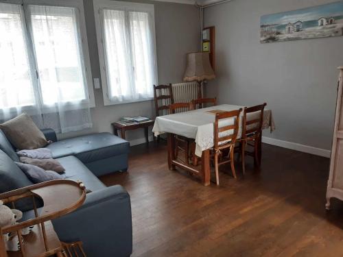 un salon avec un canapé bleu et une table dans l'établissement MAISON AU CALME A 10 MINUTE DU MONT SAINT MICHEL, à Courtils