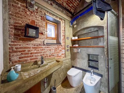 a brick bathroom with a sink and a toilet at lovingenoa Light - Passion in Genoa