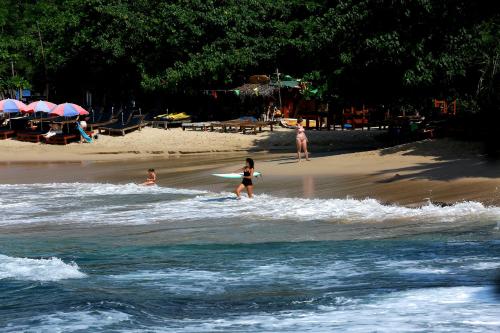 a girl walking on the beach with a surfboard at Hiriketiya Don Simon Villa in Dickwella