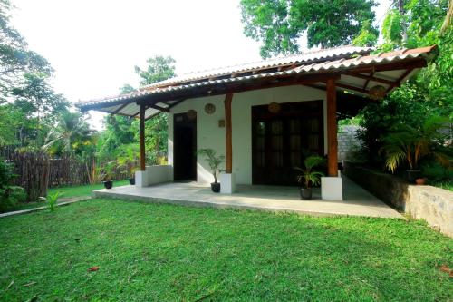 a small house with a porch and a grass yard at Hiriketiya Don Simon Villa in Dickwella