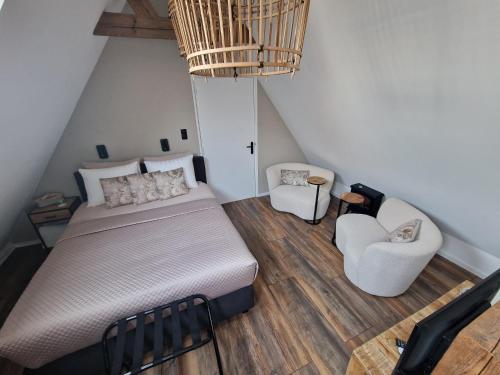a bedroom with a bed and chairs in a attic at Bij ons op de Hoep. in Schagen