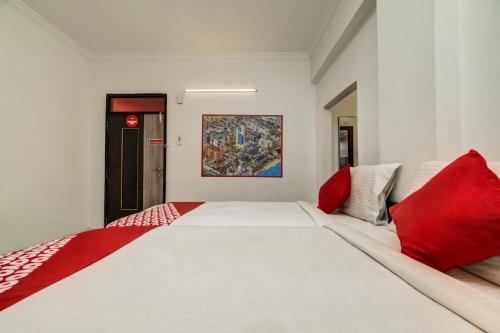 a bedroom with a large white bed with red pillows at Hotel O JNTU college Near LULU mall, KPHB Colony. in Hyderabad