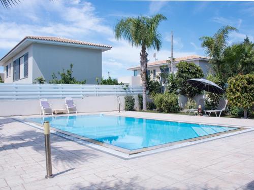 a swimming pool with two chairs and a house at Maestro Villa in Meneou