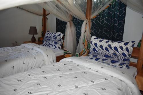 two beds in a room with white and blue pillows at Kili Kivuli in Msaranga
