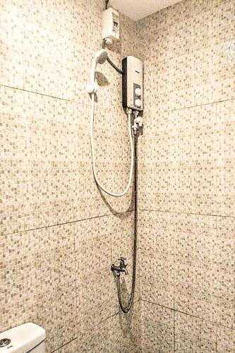 a shower in a bathroom with a shower head at Hometel Barrio House Mactan in Mactan