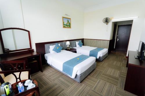 a hotel room with two beds and a mirror at Bạch Đằng Hạ Long Hotel in Ha Long