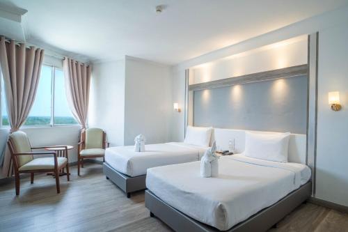 a hotel room with two beds and a table and chairs at Thong Tarin Hotel in Surin
