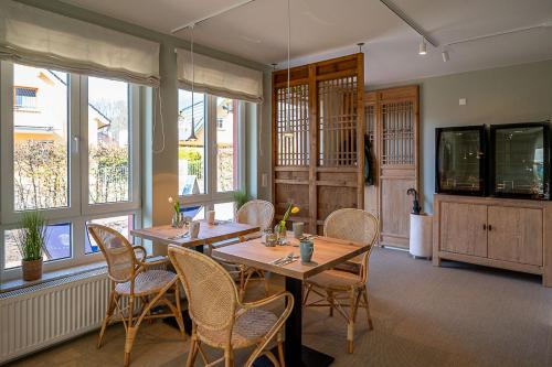 a dining room with tables and chairs and windows at Upstalsboom Koserow Boutique Hotel und Apartments in Ostseebad Koserow