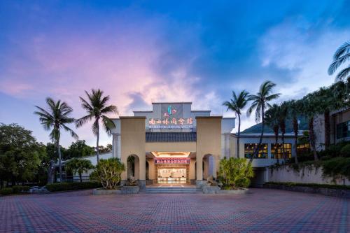 a building with palm trees in front of it at Sanya Nanshan Leisure Club Seaview Hotel in Sanya