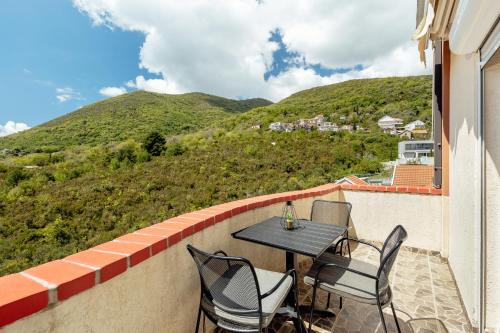 a patio with a table and chairs on a balcony at Lovely apartment with stunning view on Kotor Bay in Bijela