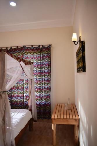 a bedroom with a bed and a wooden table at Kili Kivuli in Msaranga