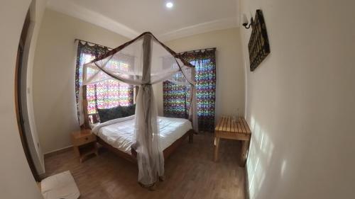 a bedroom with a canopy bed and a window at Kili Kivuli in Msaranga