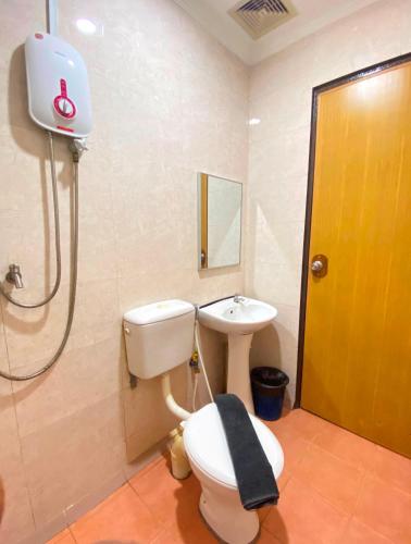 a bathroom with a toilet and a sink at The Grand Hotel 2 in Sandakan
