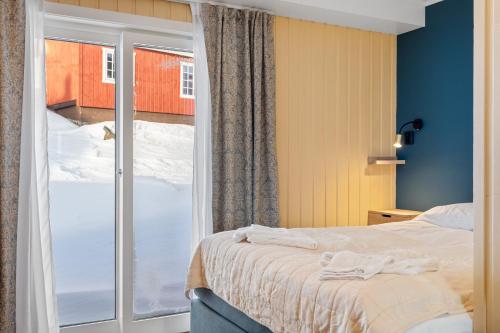a bedroom with a bed and a sliding glass door at Grønolen Fjellgard in Beitostøl