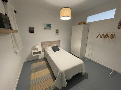 ein Schlafzimmer mit einem Bett mit weißen Laken und einem Teppich in der Unterkunft Amancay in Cedeira