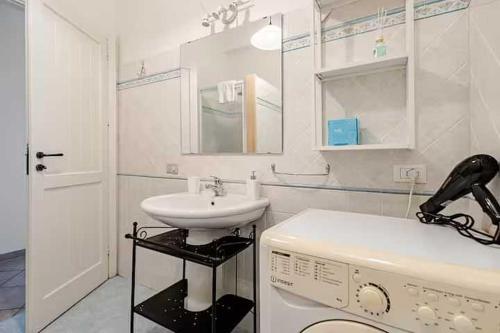a white bathroom with a sink and a washing machine at Villa Uzzo by Sicily Travelling Villas in Scopello