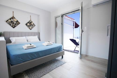 a bedroom with a blue bed and a balcony at Astra Viollonette- cozy with sea view and shared pool near the beach -BY APOKORONAS VILLAS in Kókkinon Khoríon