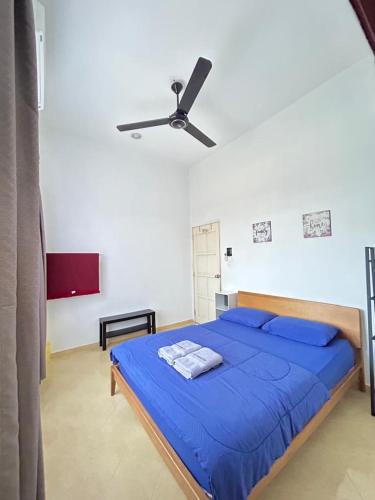 a bedroom with a blue bed with a ceiling fan at Rumah Sawah Homestay Pasir Puteh in Pasir Puteh