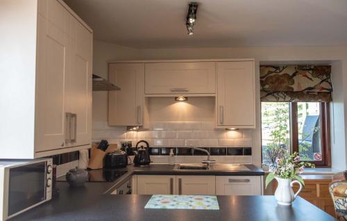 a kitchen with white cabinets and a black counter top at Ash Cottage, Castle Carrock, Nr Carlisle in Castle Carrock