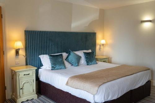 a bedroom with a large bed with blue pillows at Ash Cottage, Castle Carrock, Nr Carlisle in Castle Carrock